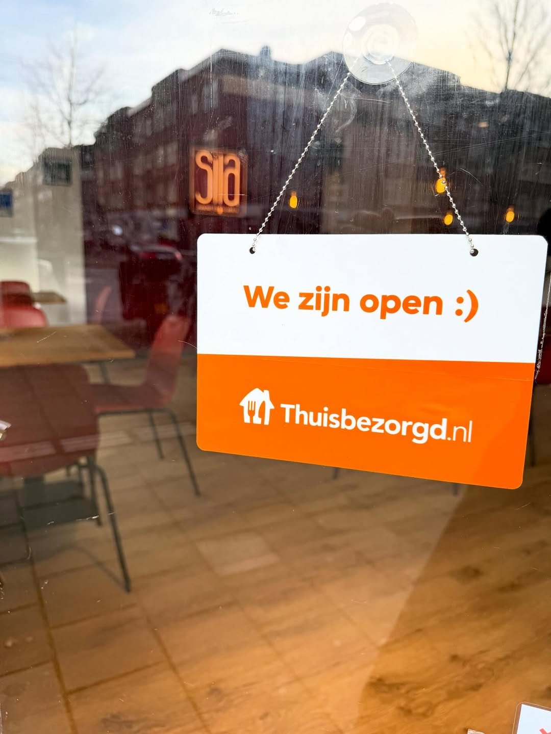 The window of Sila with the We're open sign and Thuisbezorgd
